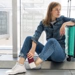femme en attente à l'aéroport pour un vol long courrier avec une valise respectant le poids maximum de la compagnie aérienne