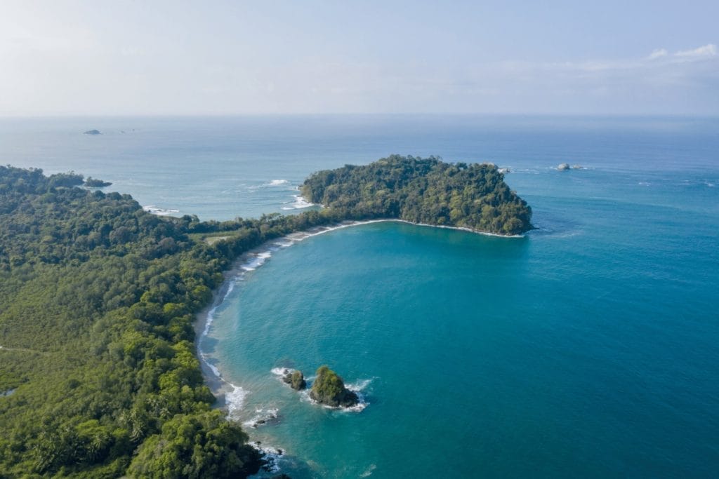 Vue aérienne du Parc National Manuel Antonio au Costa Rica, avec ses plages idylliques entourées de forêts tropicales, représentant un paradis tropical.